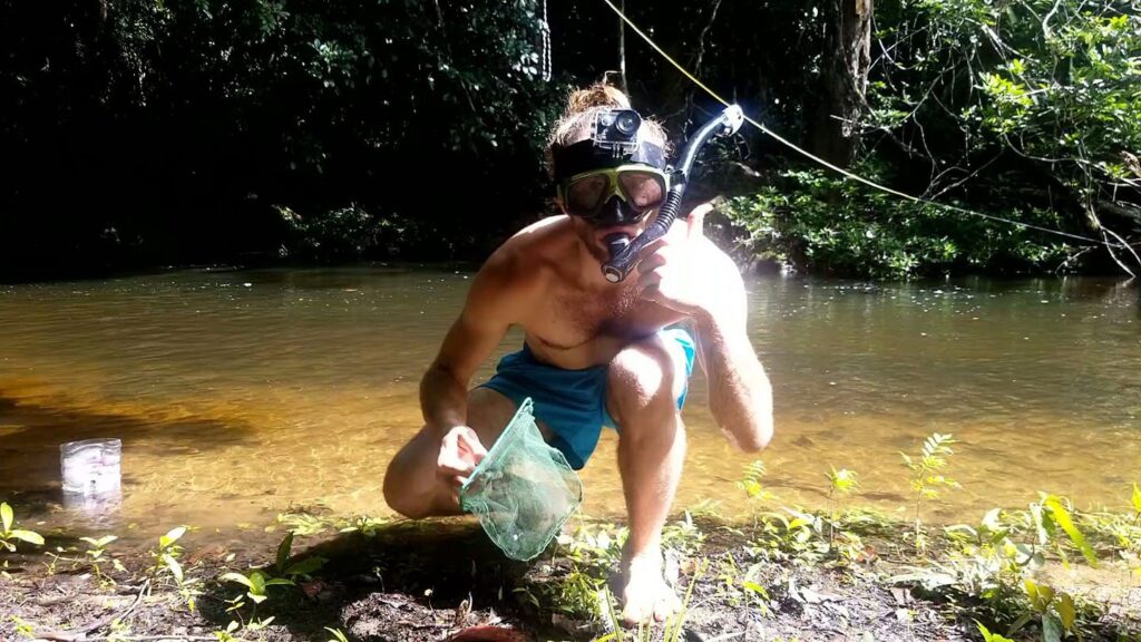 Photo of dillon wearing swim trunks, a snorkel and a holding a small fish net